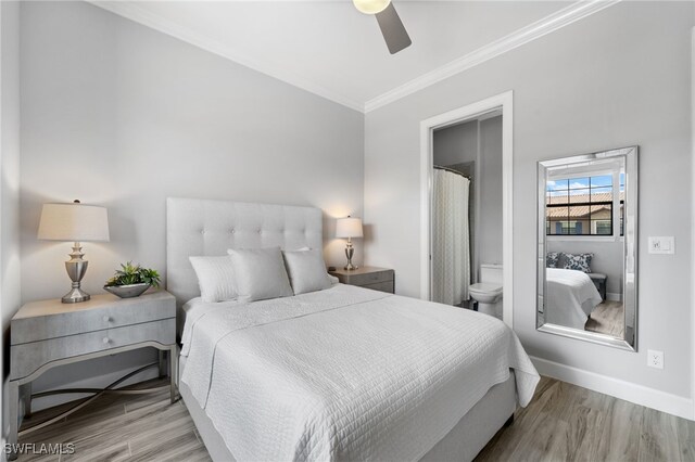 bedroom featuring ceiling fan, light wood-type flooring, crown molding, and ensuite bath