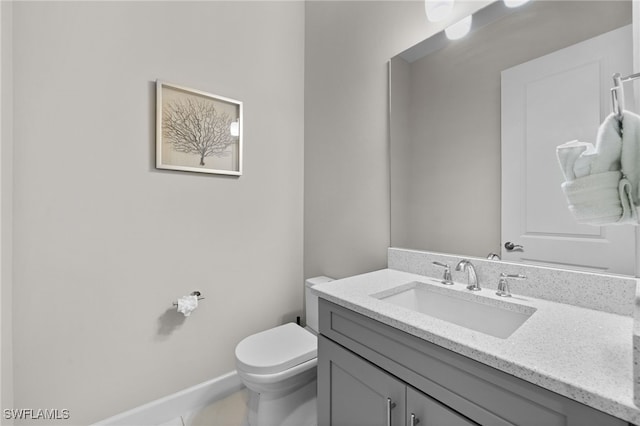 bathroom featuring baseboards, vanity, and toilet