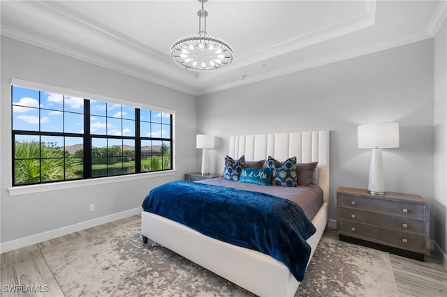 bedroom featuring ornamental molding, light hardwood / wood-style flooring, a tray ceiling, and a chandelier