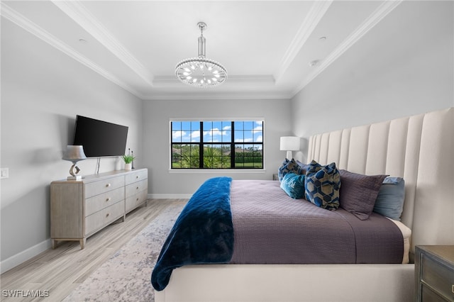 bedroom featuring a tray ceiling, crown molding, light wood-style flooring, a chandelier, and baseboards