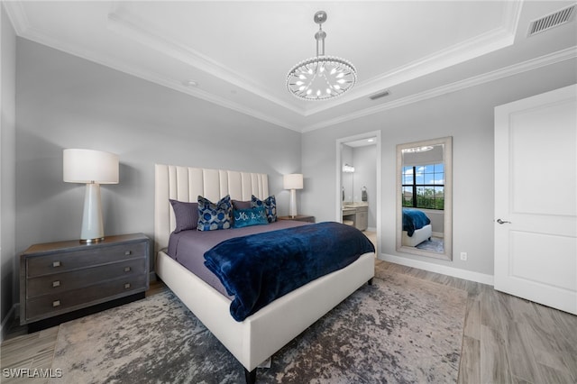 bedroom featuring visible vents, a raised ceiling, ornamental molding, wood finished floors, and an inviting chandelier