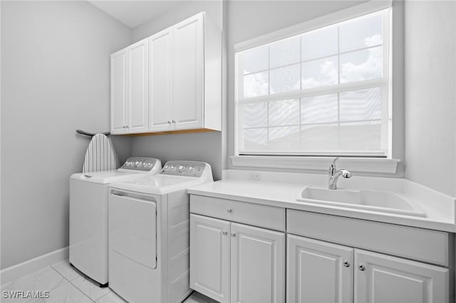 clothes washing area with washer and dryer, cabinets, light tile patterned floors, and sink