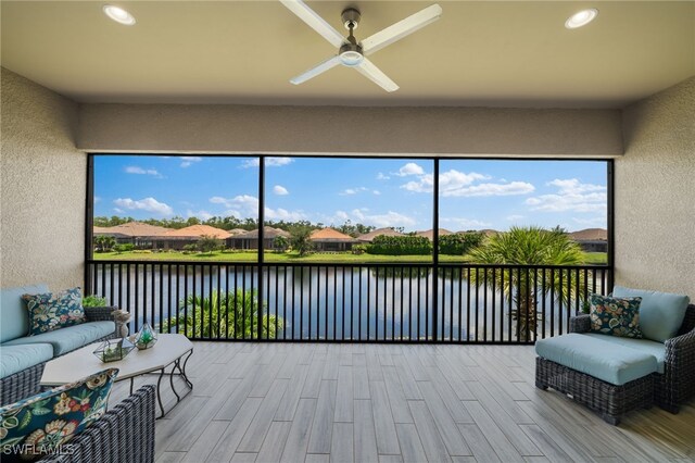 sunroom / solarium with ceiling fan and a water view