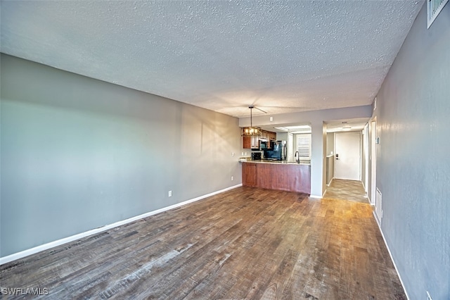 unfurnished living room featuring a textured ceiling, wood-type flooring, and an inviting chandelier