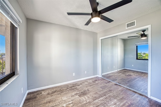 unfurnished bedroom with a textured ceiling, hardwood / wood-style floors, ceiling fan, and a closet