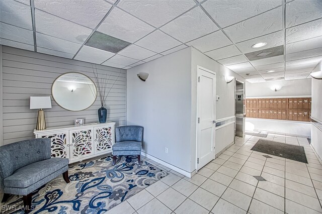 4835 Bonita Beach Rd Unit 408, Bonita Springs, FL 34134 - living area with a drop ceiling, light tile patterned flooring, wooden walls, baseboards, and mail area