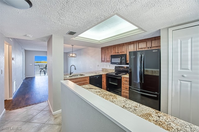 kitchen featuring a textured ceiling, decorative light fixtures, black appliances, sink, and light hardwood / wood-style floors