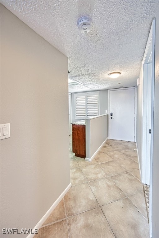 corridor with light tile patterned flooring and a textured ceiling