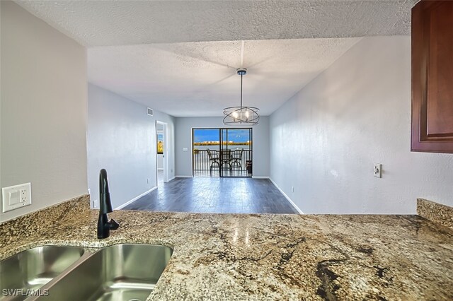 4835 Bonita Beach Rd Unit 408, Bonita Springs, FL 34134 - kitchen with a textured ceiling, stone countertops, wood finished floors, a sink, and baseboards