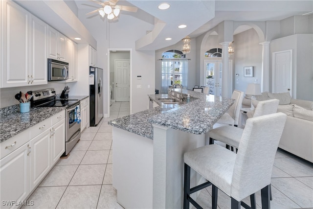 kitchen featuring white cabinets, stainless steel appliances, sink, ceiling fan, and a kitchen bar