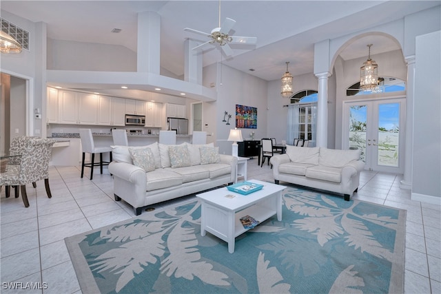 living room with light tile patterned floors, ceiling fan with notable chandelier, high vaulted ceiling, and french doors