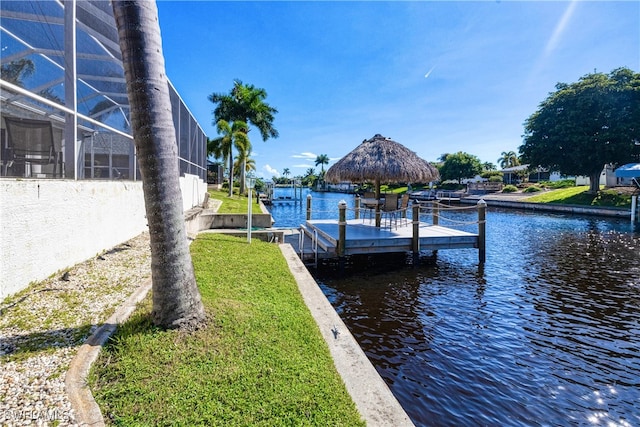 view of dock with glass enclosure, a water view, and a yard