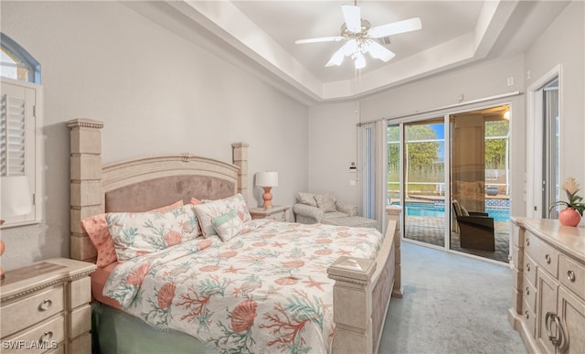 bedroom with access to exterior, ceiling fan, light carpet, and a tray ceiling