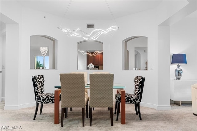 dining space featuring a notable chandelier, lofted ceiling, and light colored carpet