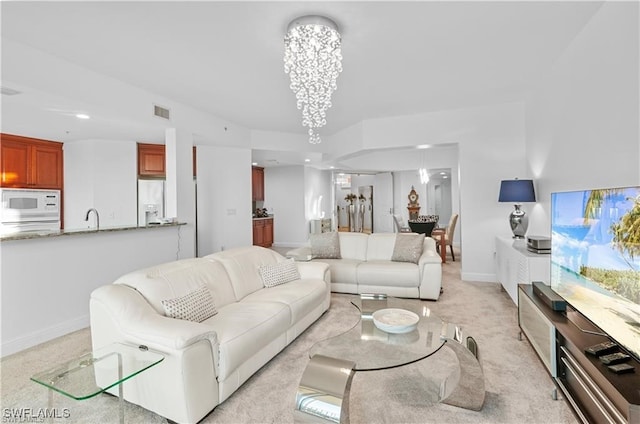 carpeted living room featuring an inviting chandelier and sink