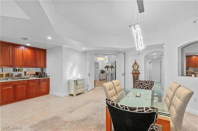 carpeted dining room with a chandelier and sink