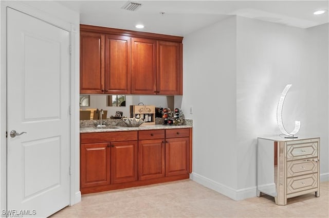 bar with light stone countertops, light tile patterned flooring, and sink