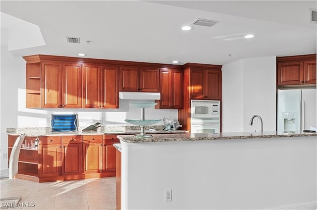 kitchen featuring sink, light stone countertops, light tile patterned floors, and white appliances