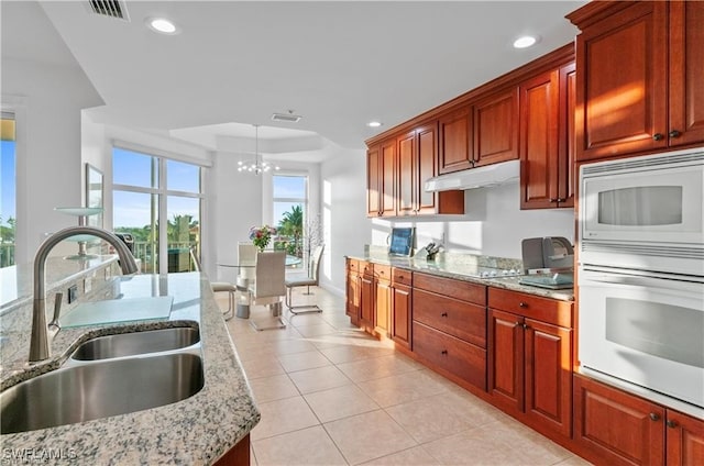 kitchen with sink, hanging light fixtures, an inviting chandelier, white appliances, and light tile patterned floors