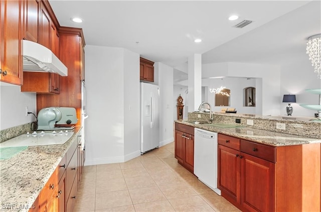 kitchen with light stone counters, an inviting chandelier, sink, and white appliances