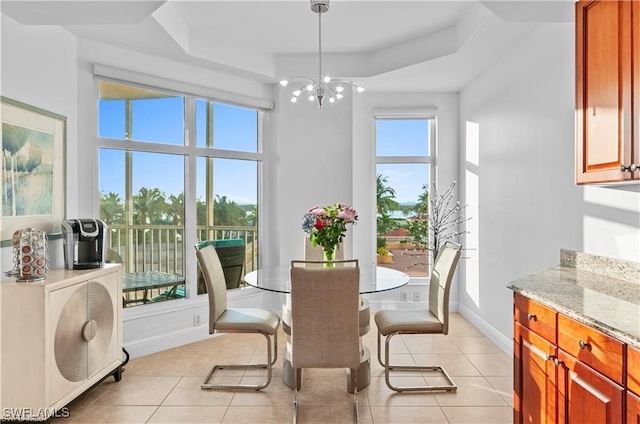 dining space featuring an inviting chandelier, a tray ceiling, and light tile patterned flooring