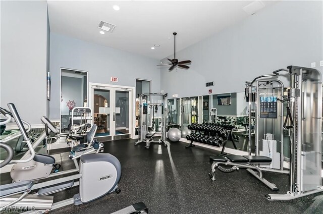 exercise room with ceiling fan and a high ceiling