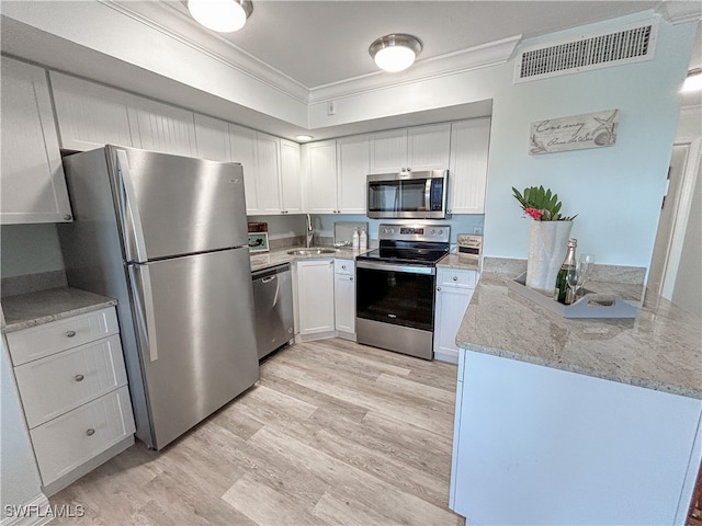 kitchen with crown molding, stainless steel appliances, light stone counters, white cabinets, and light hardwood / wood-style floors