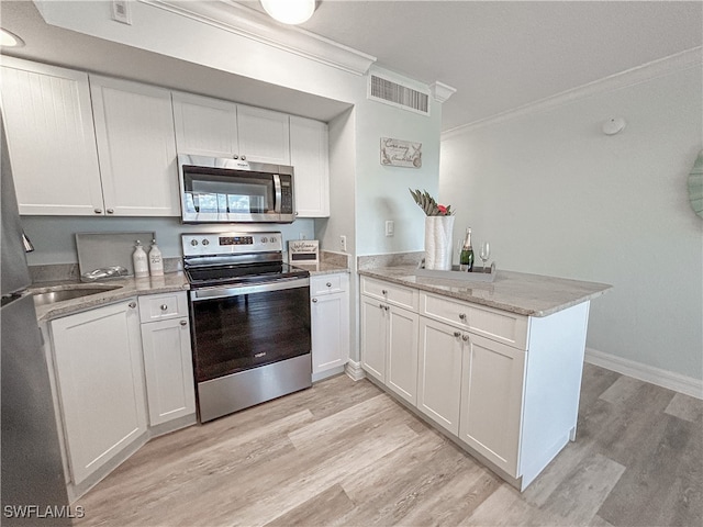 kitchen featuring kitchen peninsula, ornamental molding, appliances with stainless steel finishes, and white cabinets