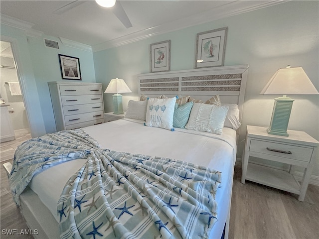 bedroom featuring light hardwood / wood-style flooring, ceiling fan, ornamental molding, and ensuite bath