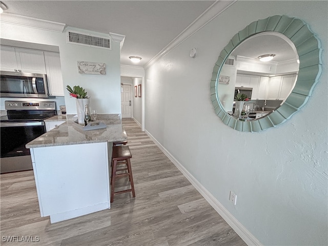 kitchen featuring light stone countertops, light hardwood / wood-style flooring, appliances with stainless steel finishes, ornamental molding, and white cabinets