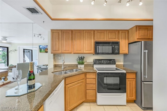 kitchen featuring light tile patterned floors, white appliances, sink, dark stone counters, and ceiling fan