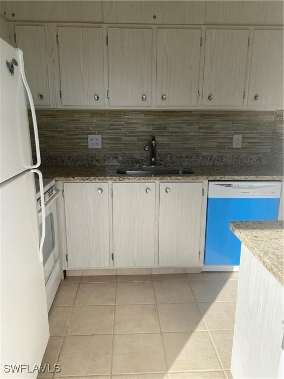 kitchen with white appliances, tasteful backsplash, a sink, and light tile patterned flooring