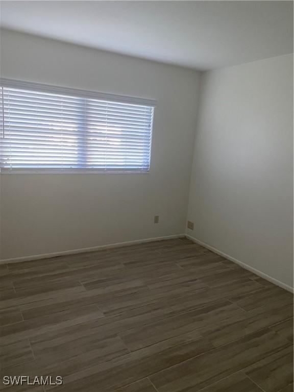 unfurnished room featuring dark wood-type flooring and a healthy amount of sunlight