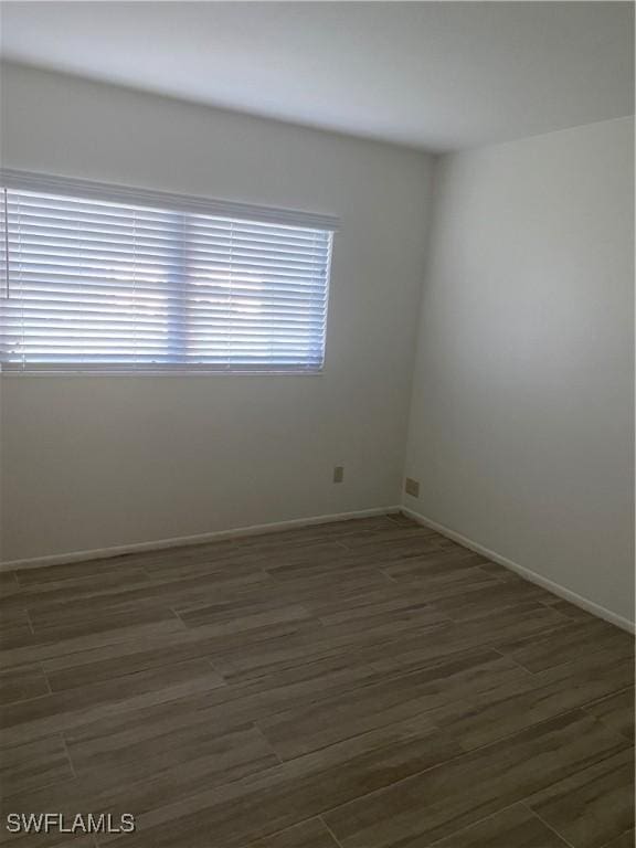 spare room with dark wood-style flooring and baseboards