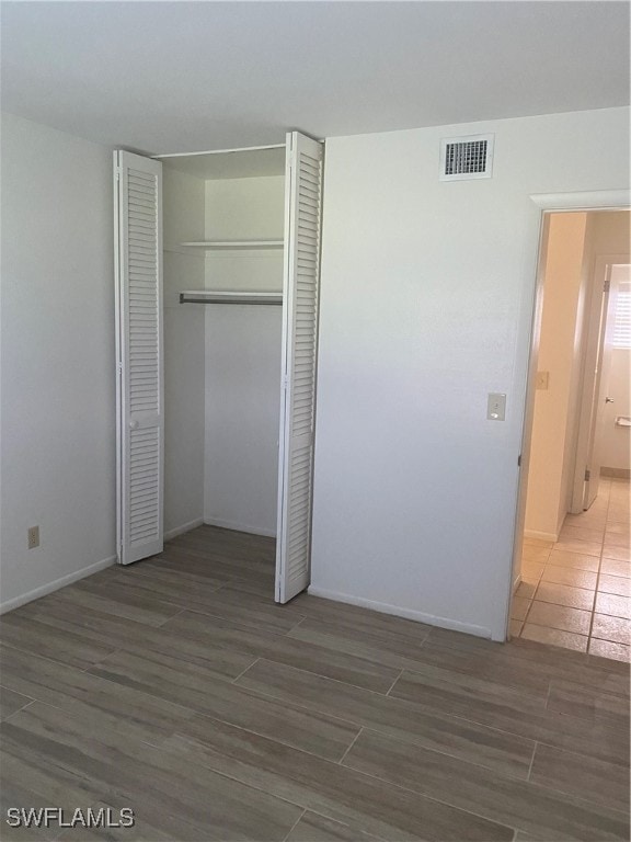 unfurnished bedroom with dark hardwood / wood-style floors and a closet