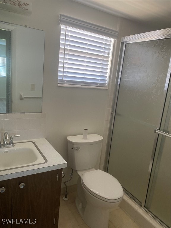 bathroom featuring a shower with shower door, tile patterned flooring, toilet, and vanity