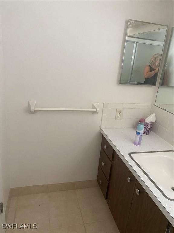 bathroom featuring tasteful backsplash, baseboards, tile patterned flooring, and vanity