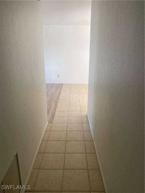 hallway featuring light tile patterned flooring and baseboards