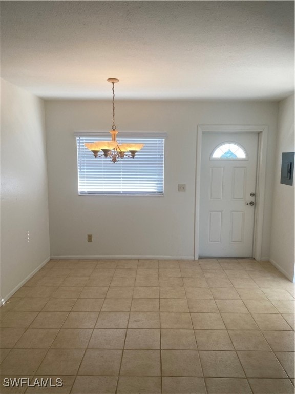 tiled foyer entrance with electric panel and a notable chandelier