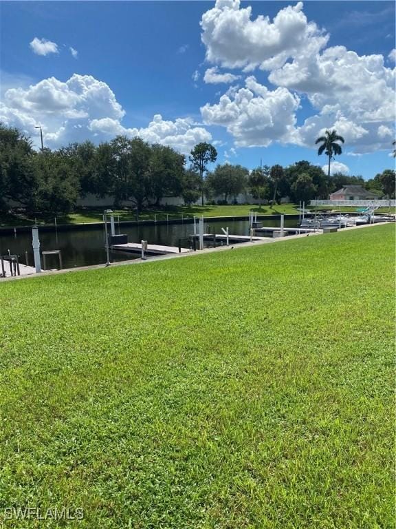 view of community with a boat dock, a water view, and a lawn