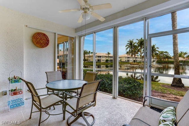 sunroom with plenty of natural light, ceiling fan, and a water view