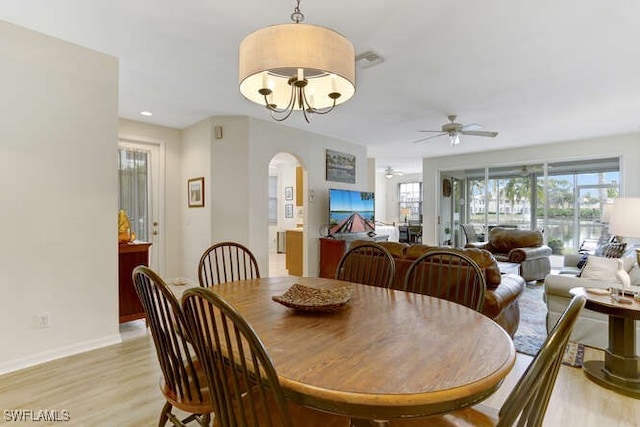 dining space featuring light wood-type flooring and ceiling fan with notable chandelier