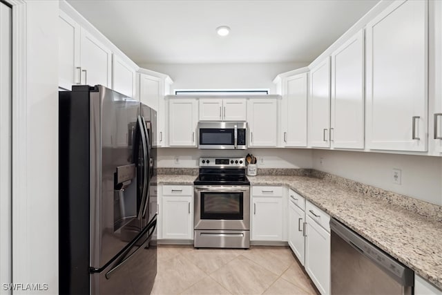 kitchen featuring stainless steel appliances, light stone counters, light tile patterned floors, and white cabinets