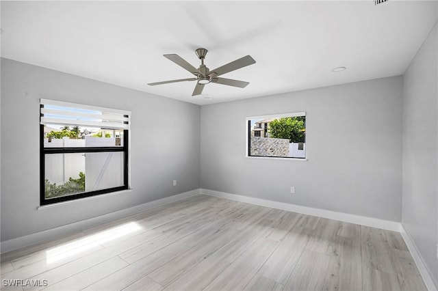 unfurnished room with light wood-style floors, a ceiling fan, and baseboards