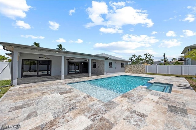 view of swimming pool featuring a pool with connected hot tub, ceiling fan, fence, and a patio