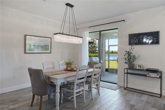 dining space featuring hardwood / wood-style floors, an inviting chandelier, and crown molding