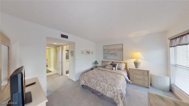 bedroom featuring connected bathroom and light carpet