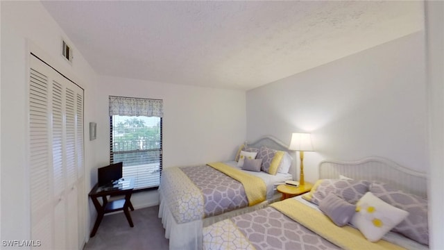 carpeted bedroom with a textured ceiling and a closet