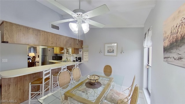 tiled dining room featuring ceiling fan, lofted ceiling, and sink