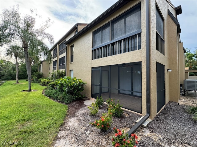 view of side of property with a lawn, a balcony, a patio, and central AC unit